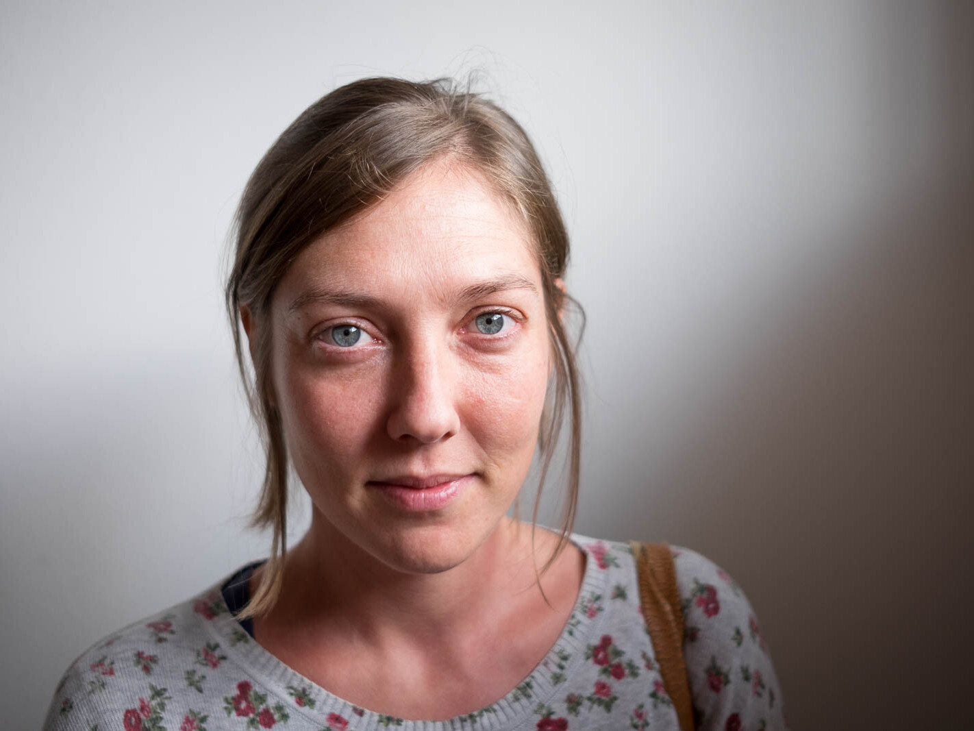 Portrait of a woman with dark blond hair and blue eyes, smiling at the camera