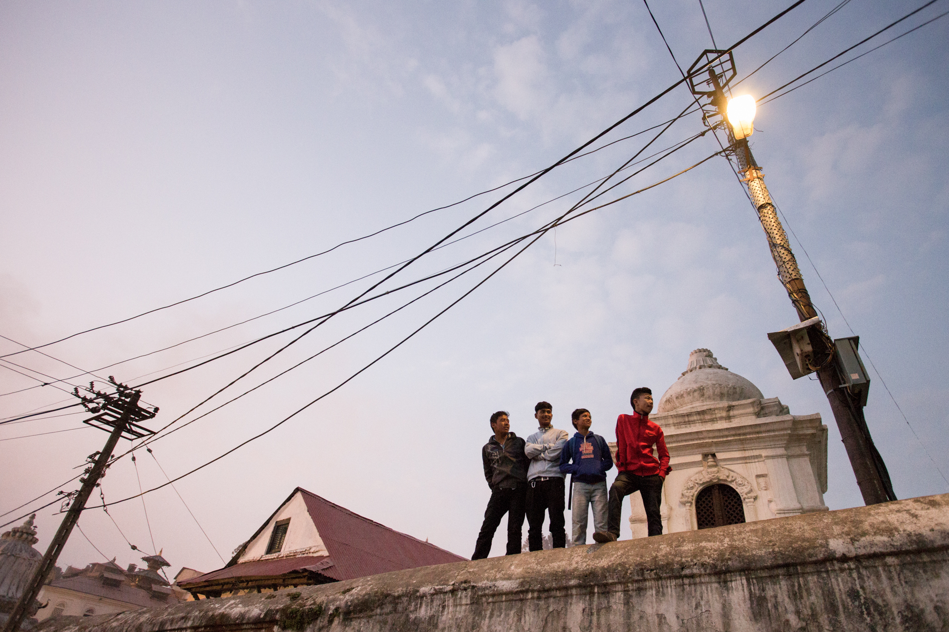 Kathmandu, Nepal. A group of friends hanging out on a wall inside the Pashupatinath temple.