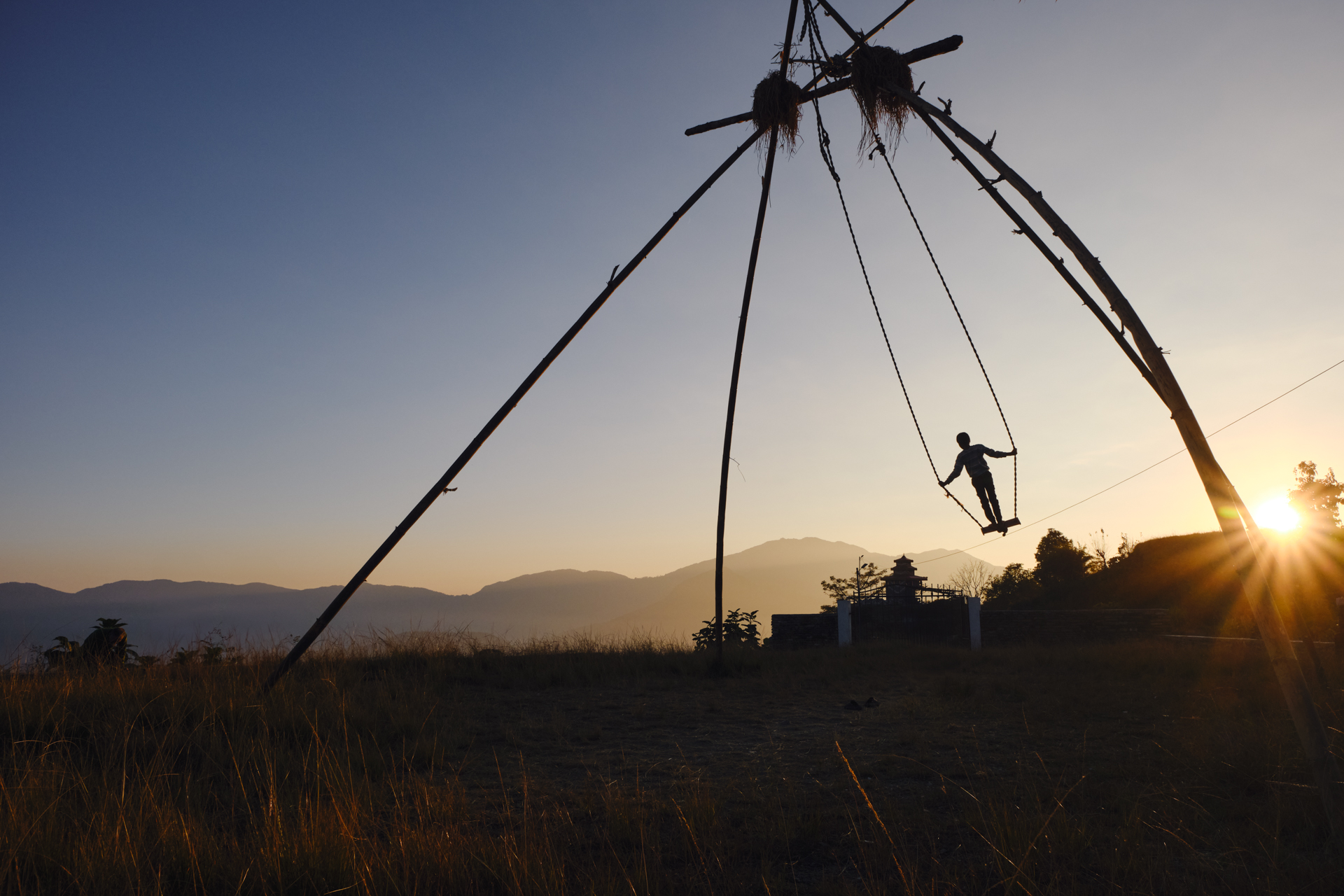 A child on a tall swing, made of bamboo for the Dashain festival period in Nepal. A Lorenz Berna's travel photography