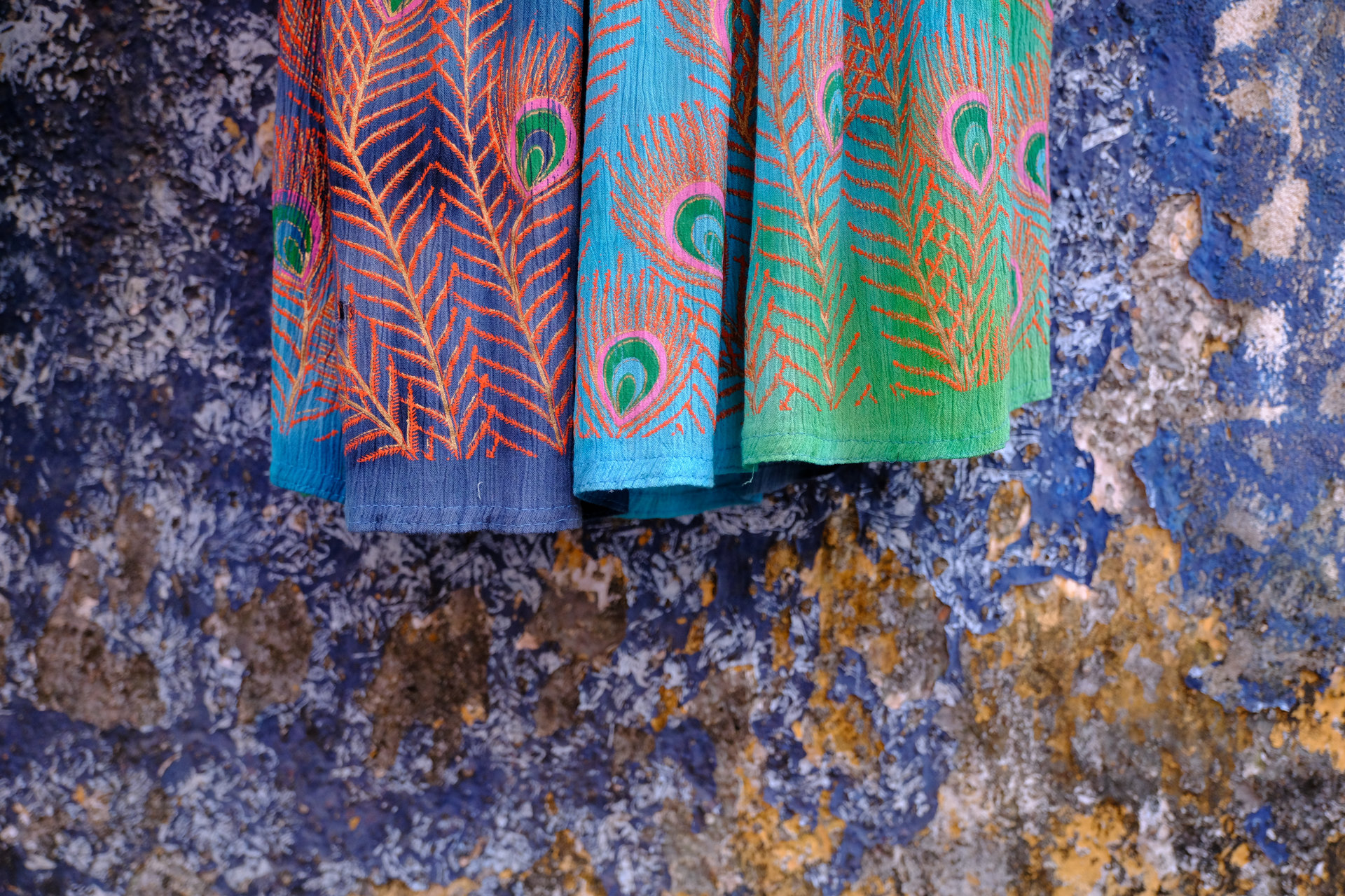 Vibrant traditional Kerala textiles hanging against a textured blue wall in Fort Kochi