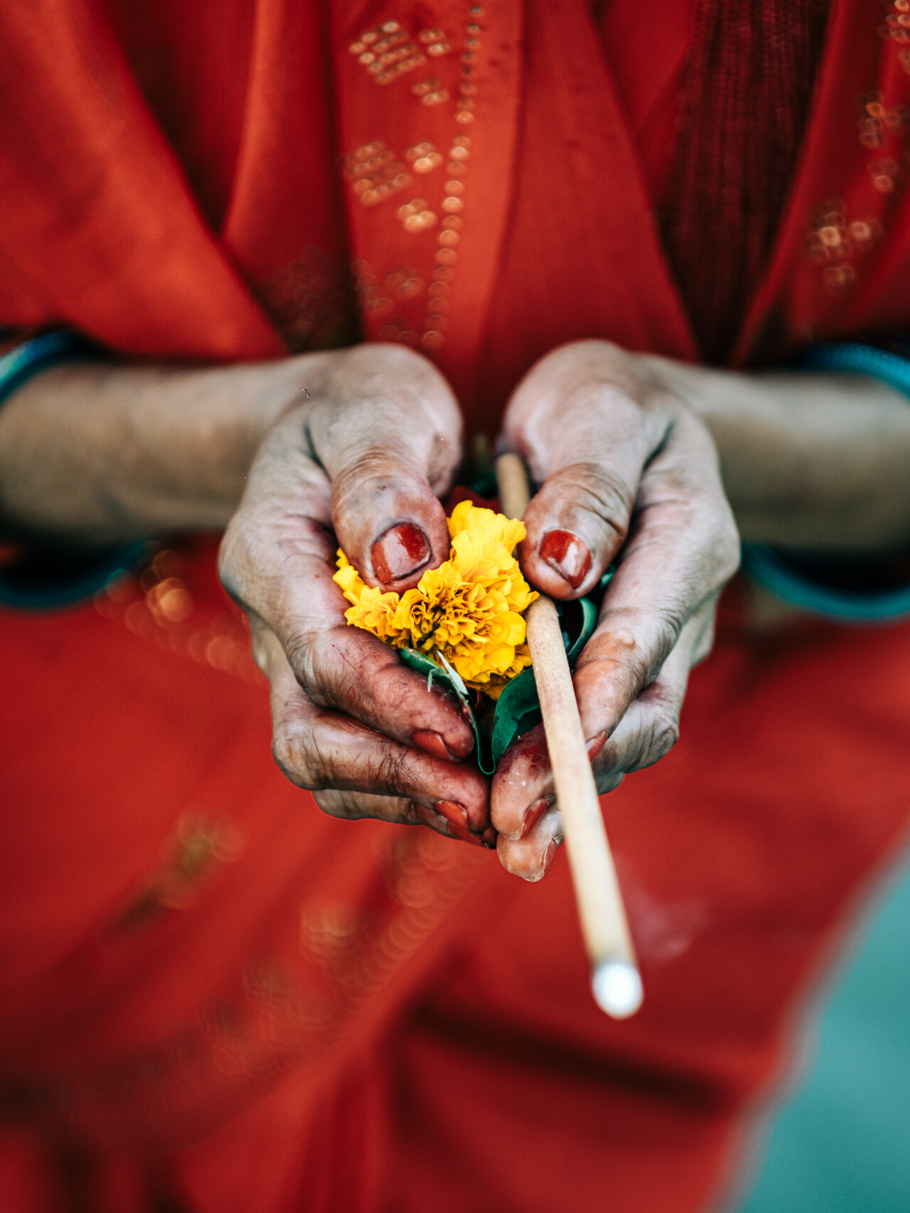 Close-up on the hands of a woman holding offerings at the Chhat Puja in Kathmandu. A Nepal photography by Lorenz Berna