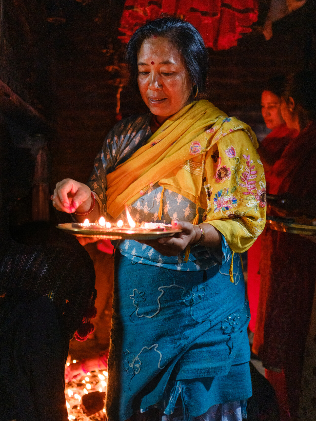 Woman celebrating the Aarti, during the night of Laxmi Puja on the Nepali Tihar Festival. Nepal photography by Lorenz Berna