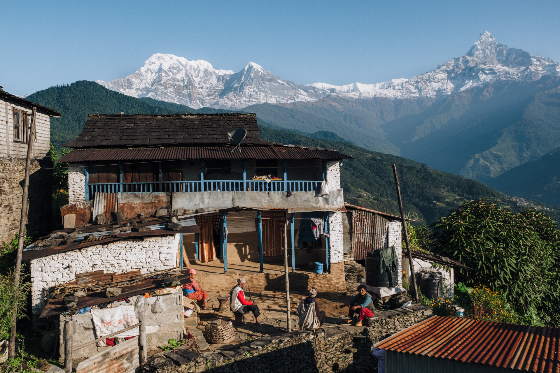 Locals sitting in front of a traditional house with snow-capped peaks in background – authentic life in Dhampus village