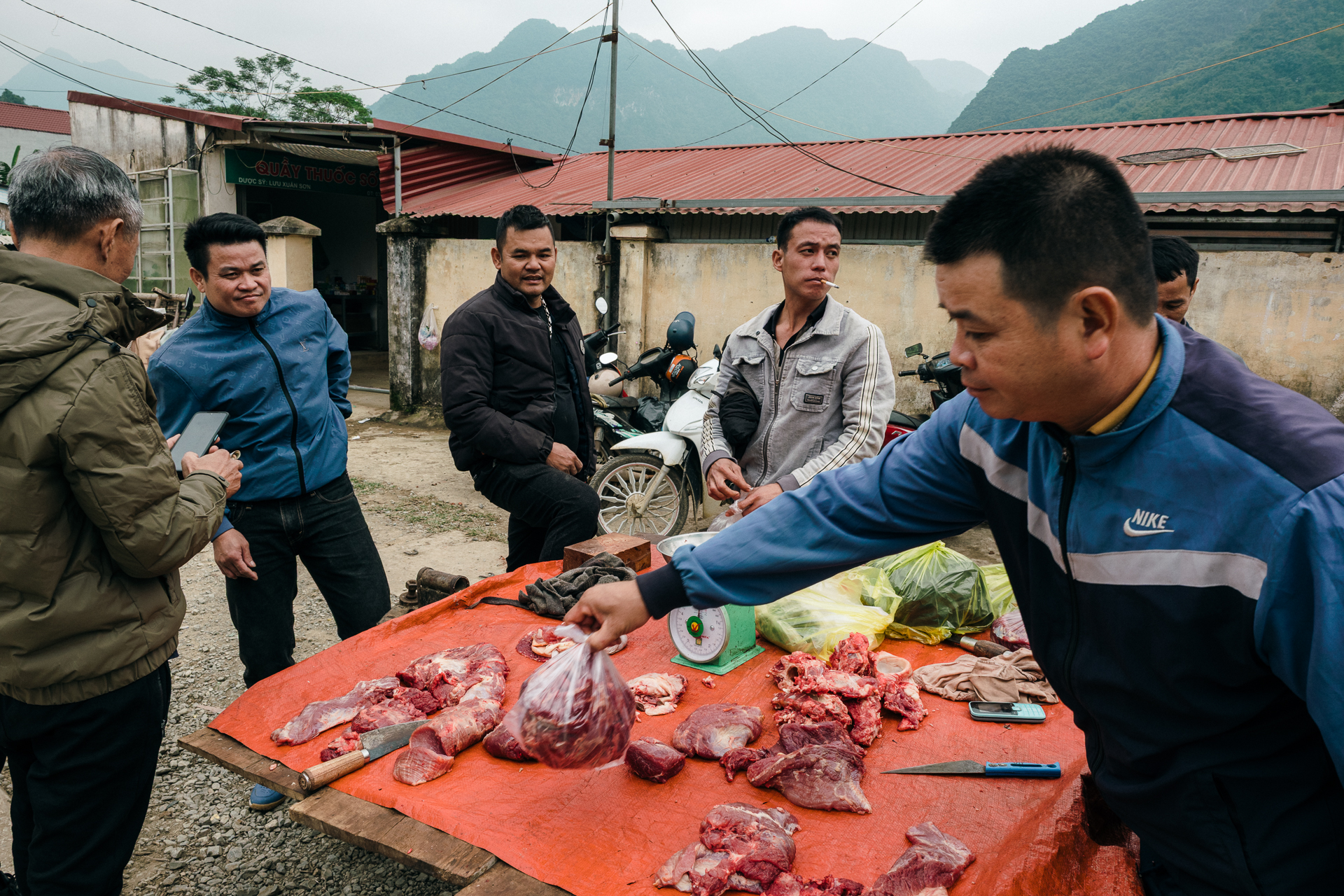 Village market scene in Pu Luong, Vietnam, with men gathering around a butcher’s table.